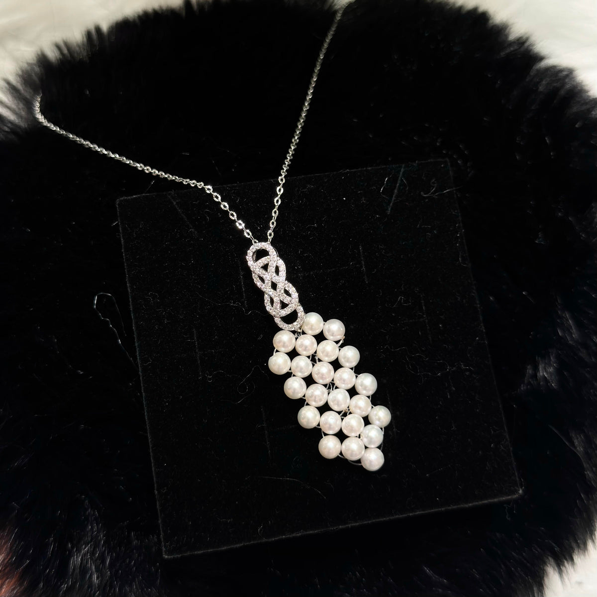 Close-up of geometric woven white freshwater pearl pendant.