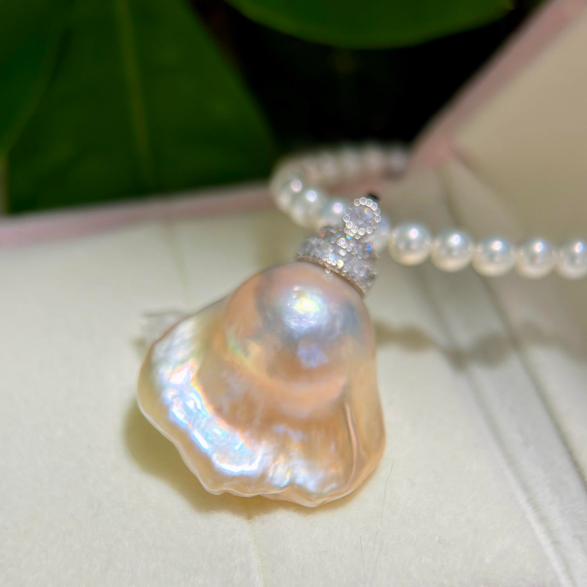 Statement jewelry design featuring golden-blue baroque freshwater pearl pendant with light golden halo and universal sterling silver bail.