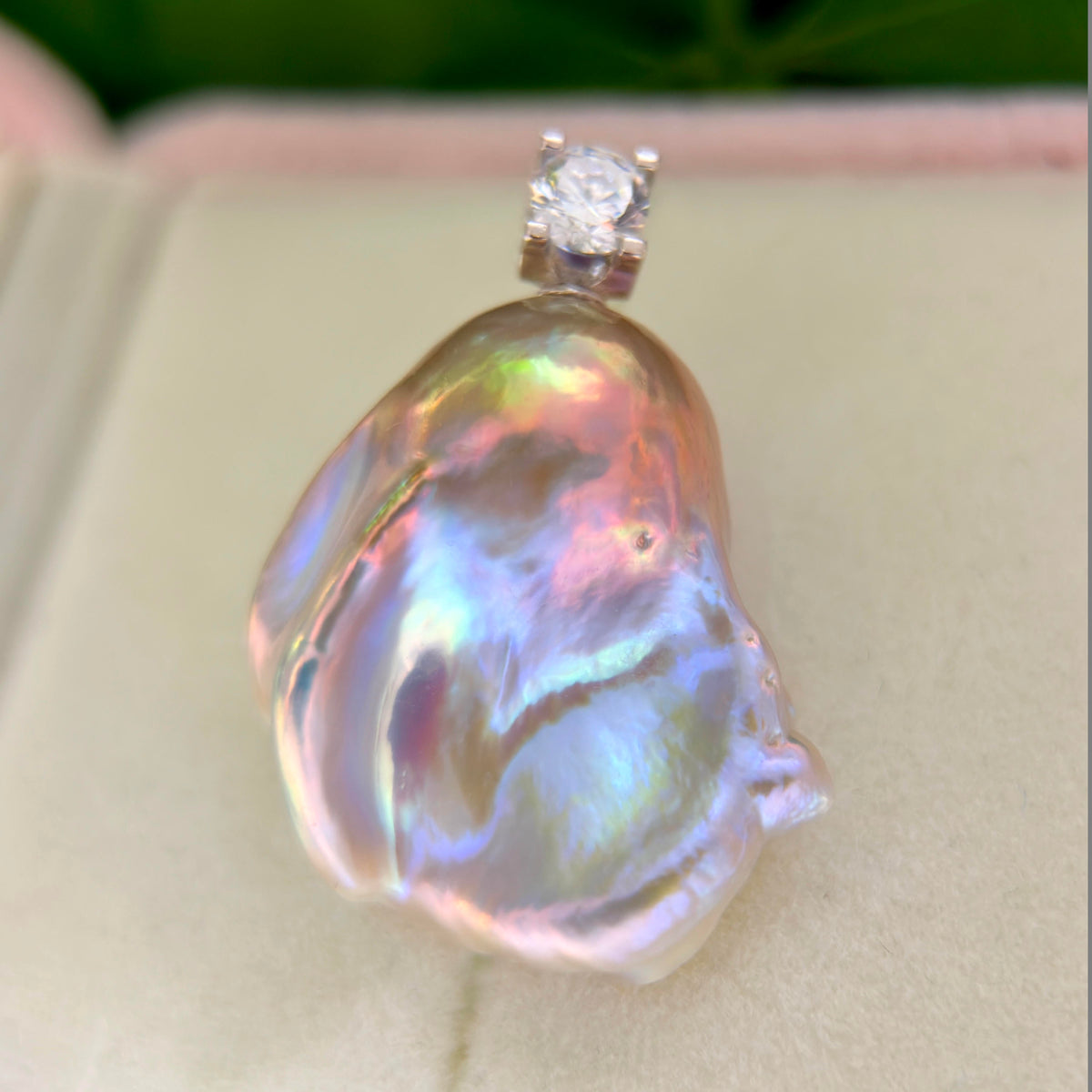 Whimsical blue baroque freshwater pearl pendant with colorful iridescent halo and silver setting.