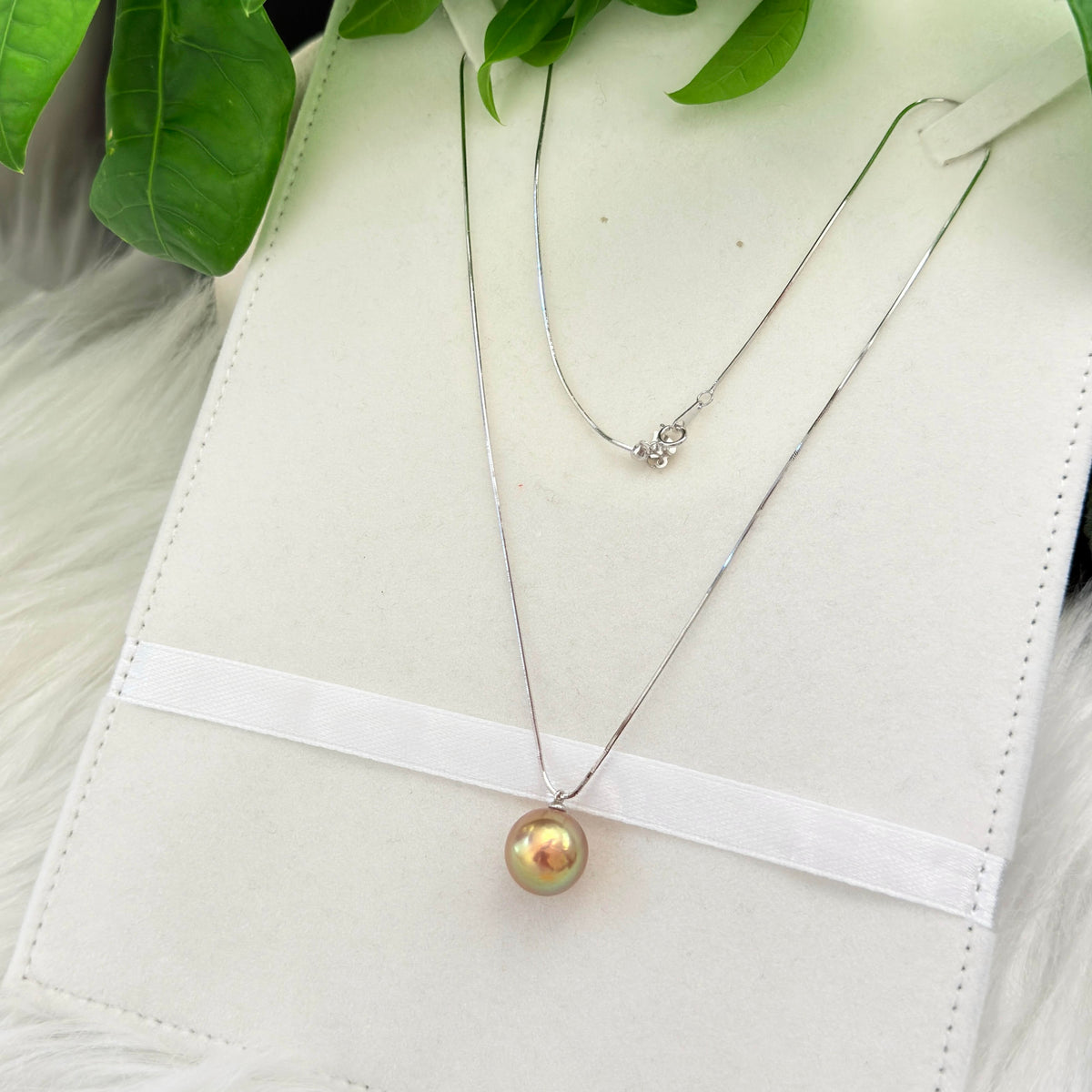 Minimalist single-pearl necklace styled for day-to-night wear.