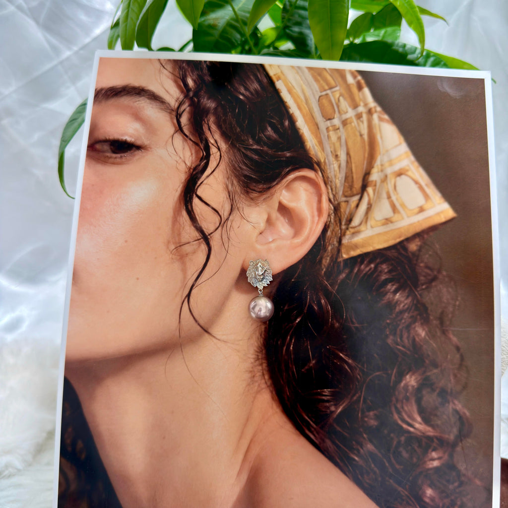 Model wearing metallic bronze pearl drop earrings.