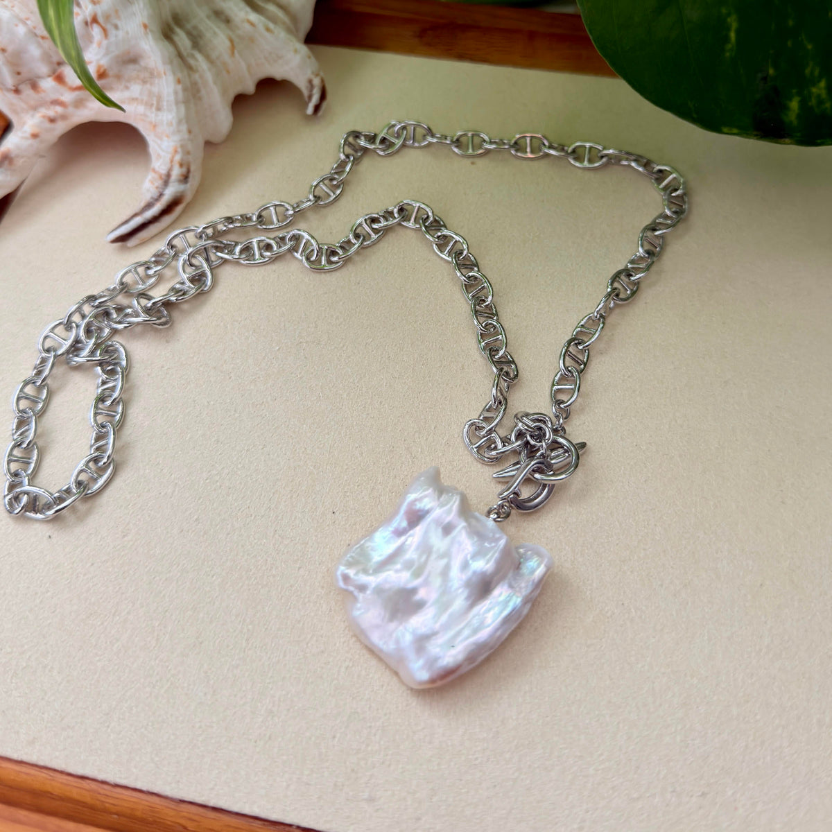 Detailed product view of white square baroque freshwater pearl pendant on chunky white-gold-plated chain.
