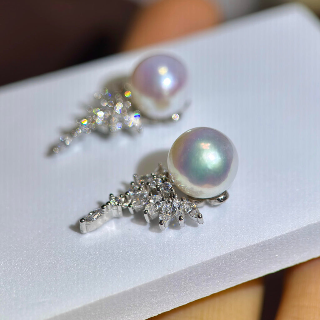 A pair of silver-toned statement earrings featuring large iridescent freshwater pearls and sparkling clear crystal clusters, displayed on a white card.