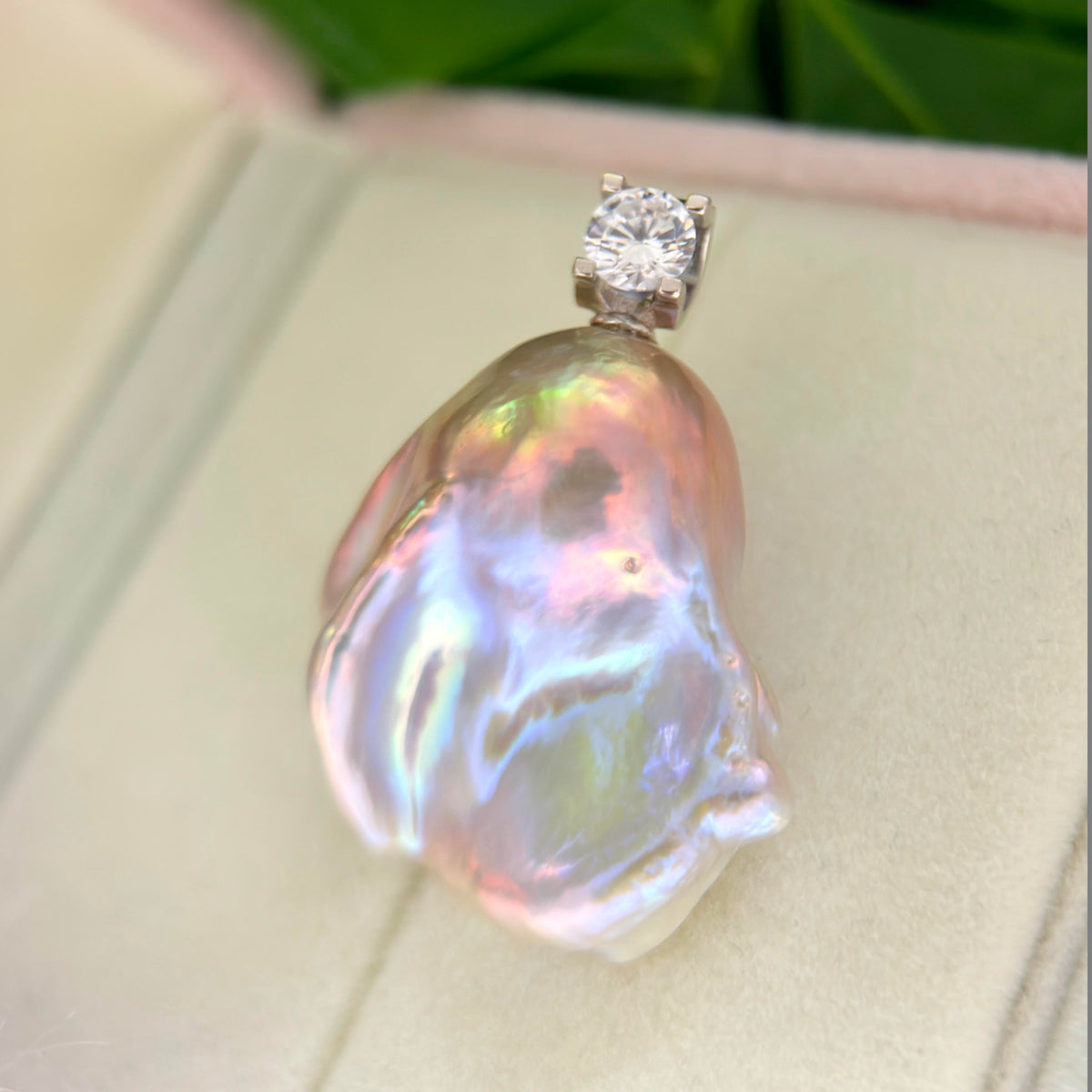 Close-up of whimsical blue baroque freshwater pearl pendant with colorful iridescent halo and silver setting.
