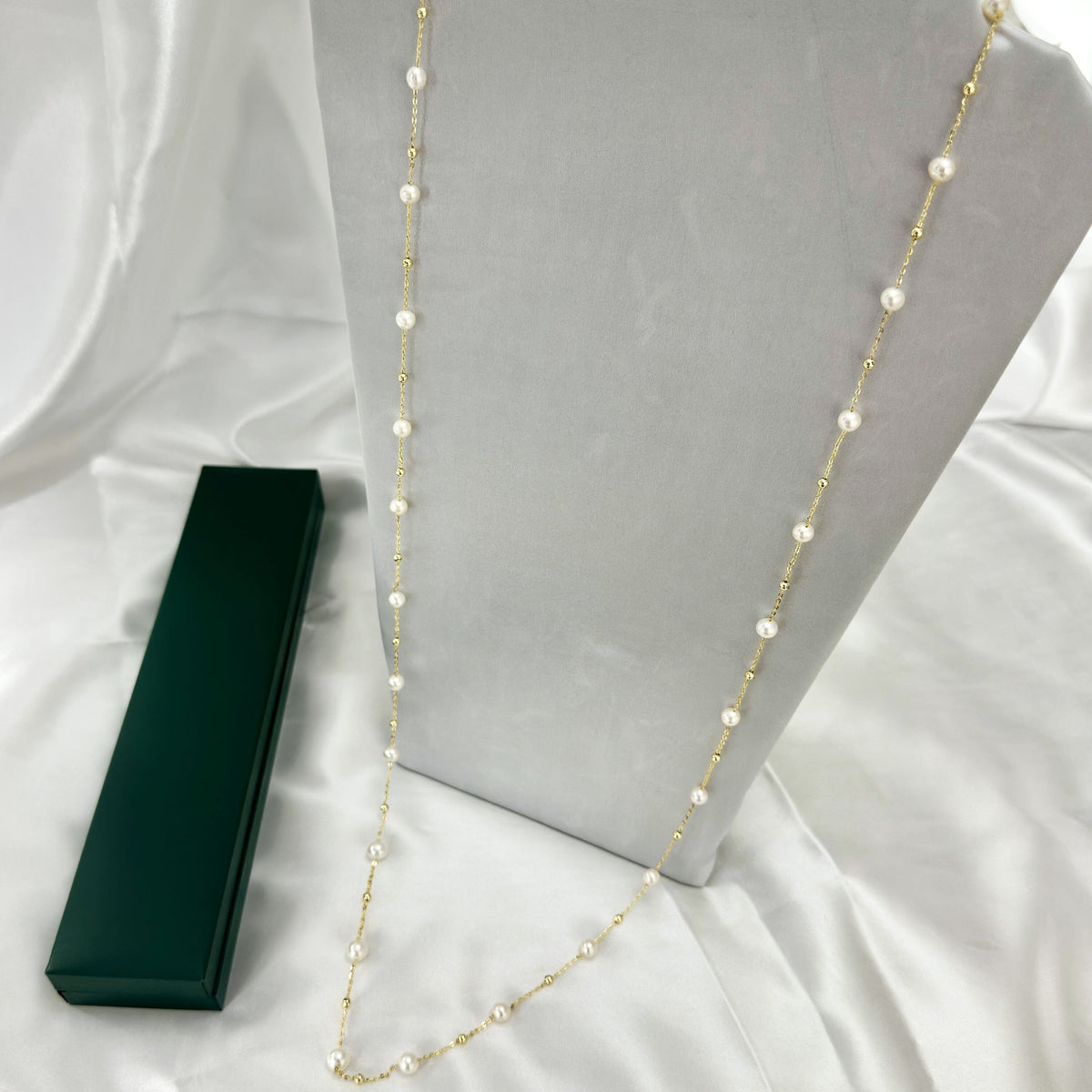 Long white freshwater pearl necklace spaced along a delicate gold-tone chain.
