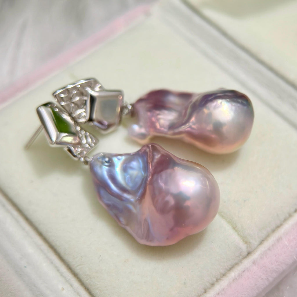 Close-up of purple-blue baroque freshwater pearl earrings with asymmetric geometric sterling silver frames.