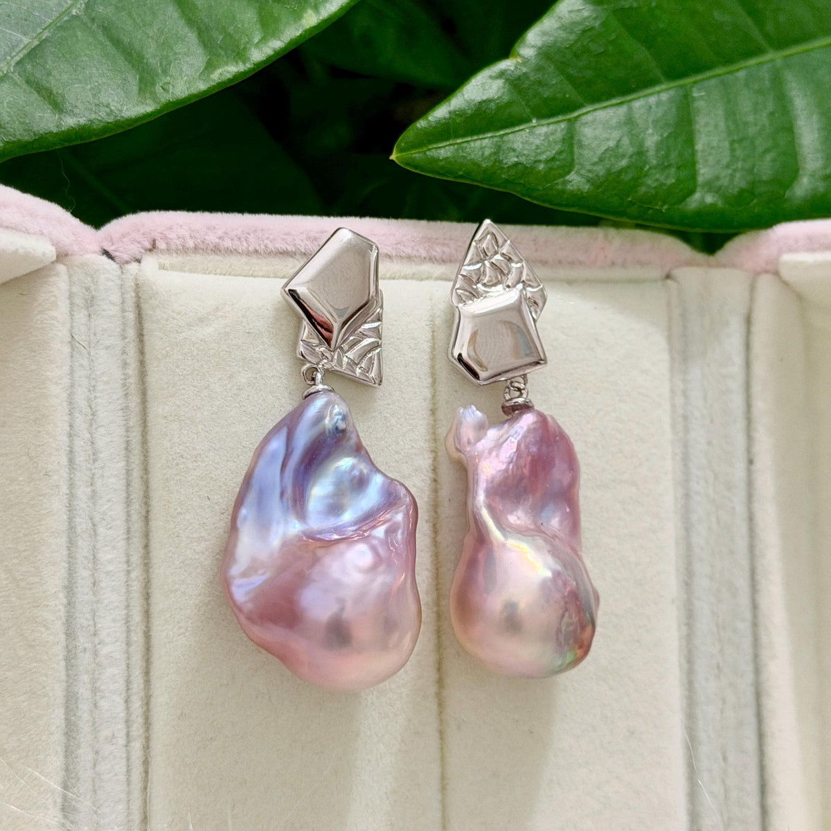 Detailed product view of purple-blue baroque freshwater pearl earrings with asymmetric geometric sterling silver frames.