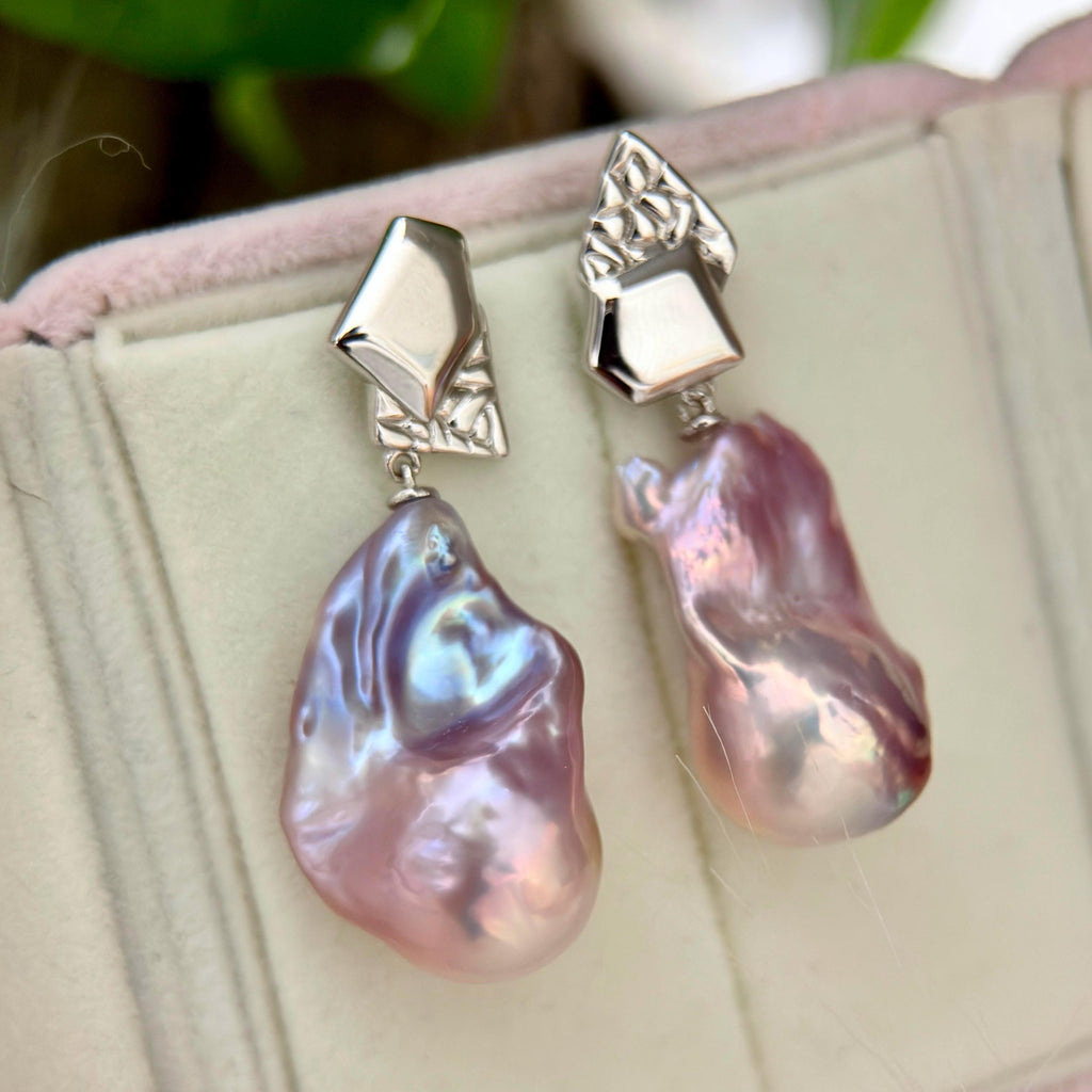 Colour-shifting detail on purple-blue baroque freshwater pearl earrings with asymmetric geometric sterling silver frames.