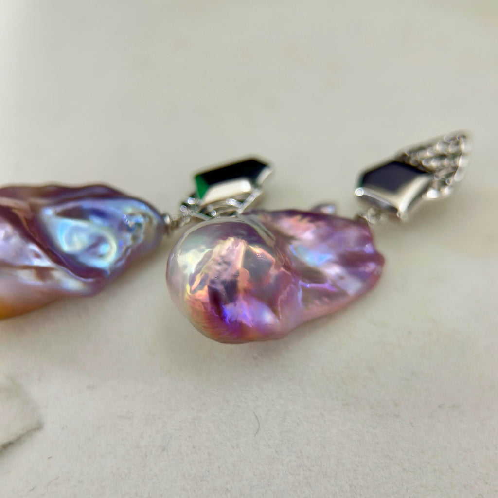 Statement jewelry design featuring purple-blue baroque freshwater pearl earrings with asymmetric geometric sterling silver frames.