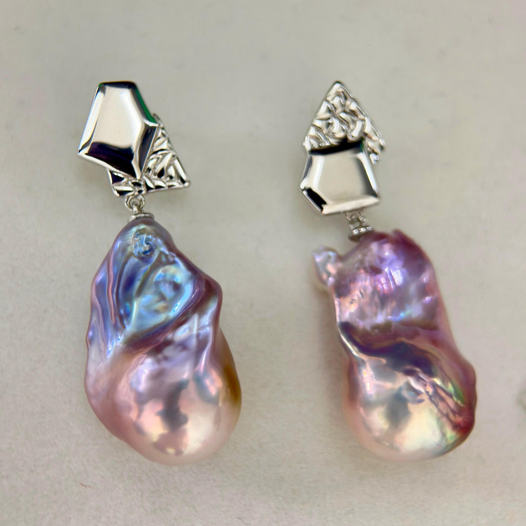 Iridescent halo detail on purple-blue baroque freshwater pearl earrings with asymmetric geometric sterling silver frames.