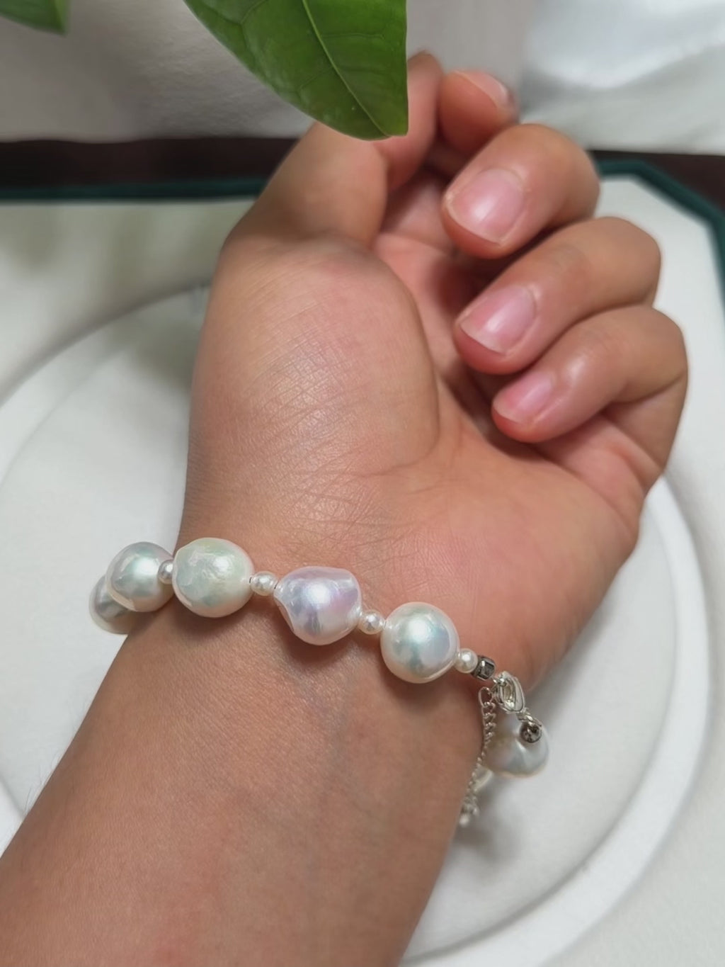 Design detail of white ruffled baroque freshwater pearl bracelet with blue-pink iridescence and small pearl accents.