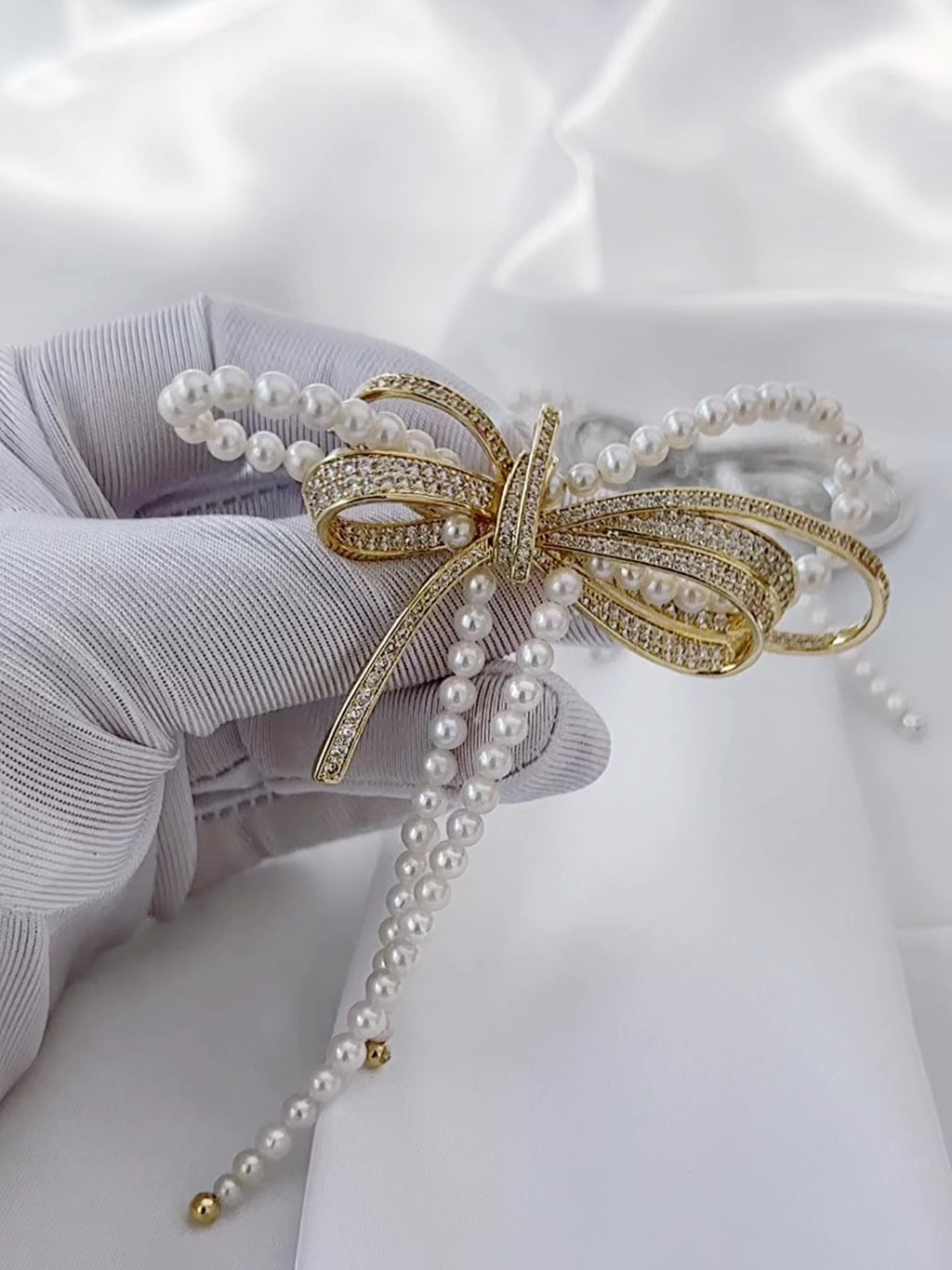 Gold-tone freshwater pearl bow brooch with elegant statement styling.
