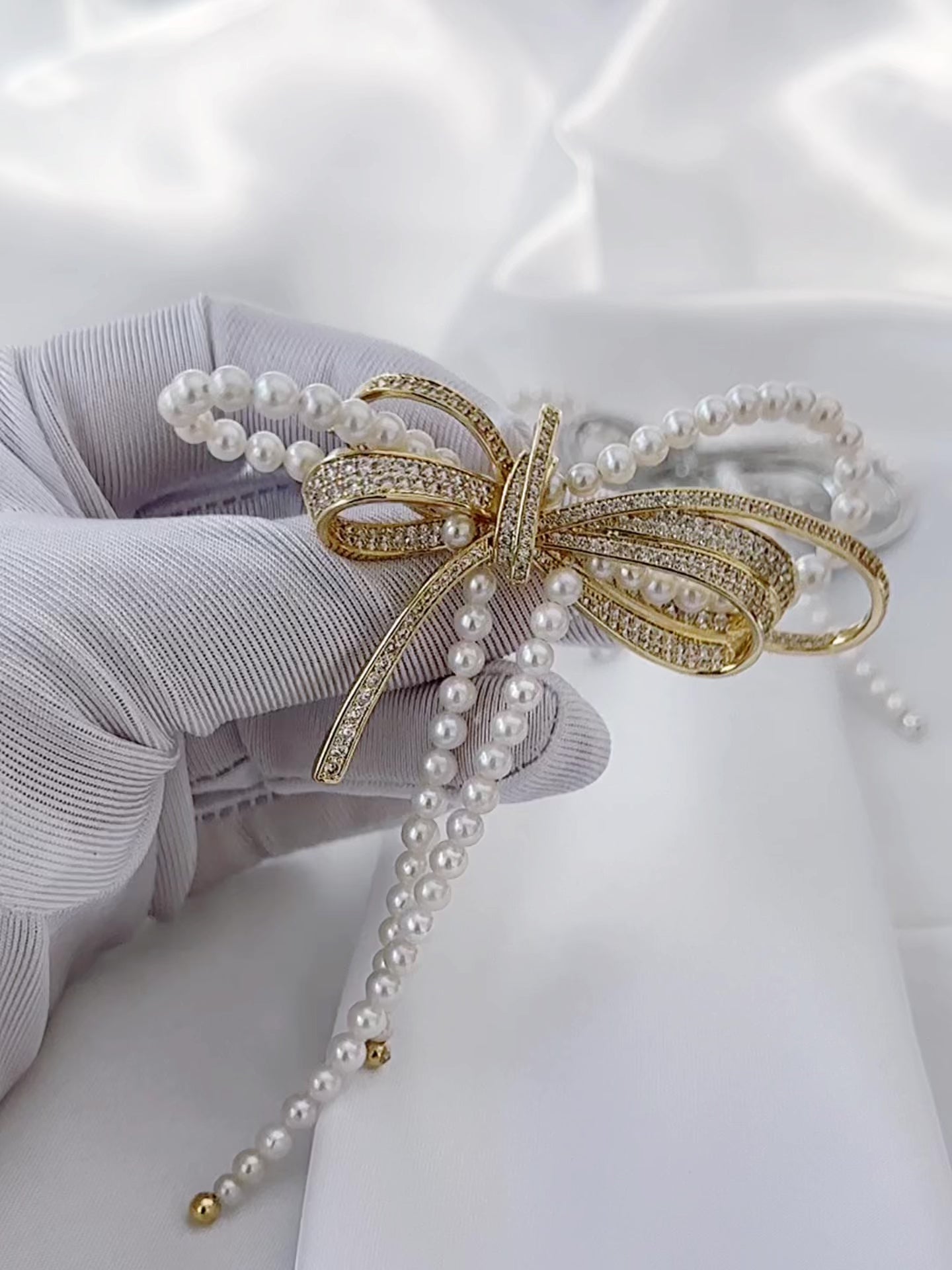 Gold-tone freshwater pearl bow brooch with elegant statement styling.