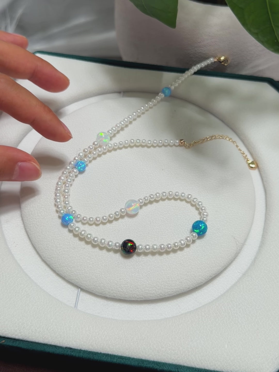 Luminous white pearl necklace decorated with colourful opal beads resembling planets.