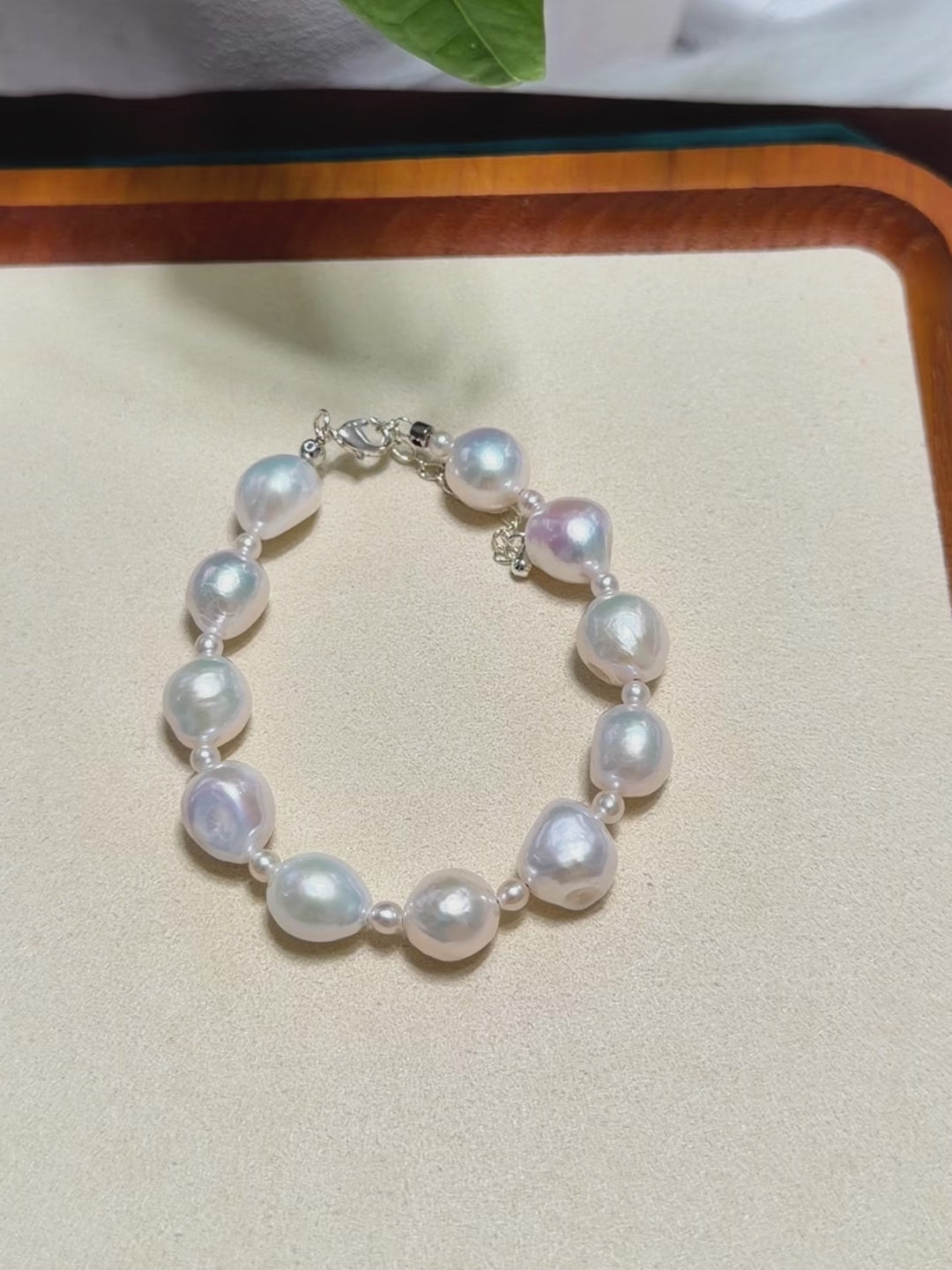 Colour-shifting detail on white ruffled baroque freshwater pearl bracelet with blue-pink iridescence and small pearl accents.