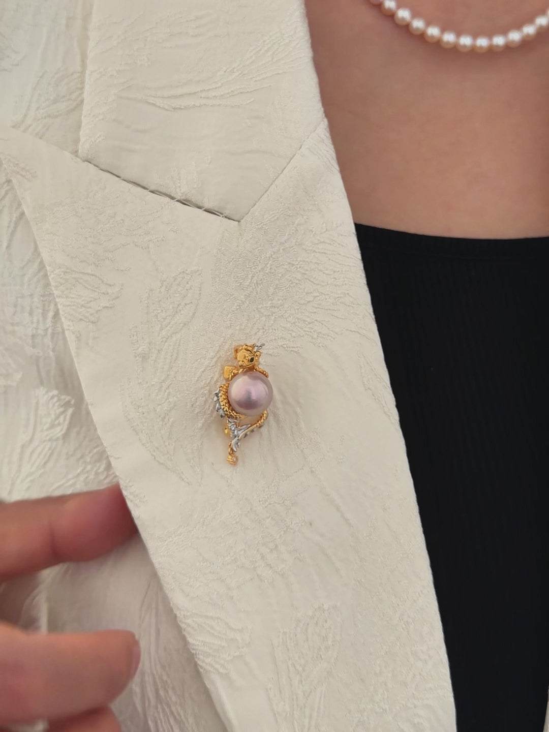 Model wearing a dragon pearl brooch as a statement accessory.