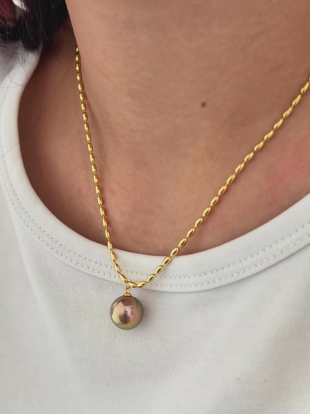 Colour-shifting pearl necklace styled as minimalist collarbone jewelry.
