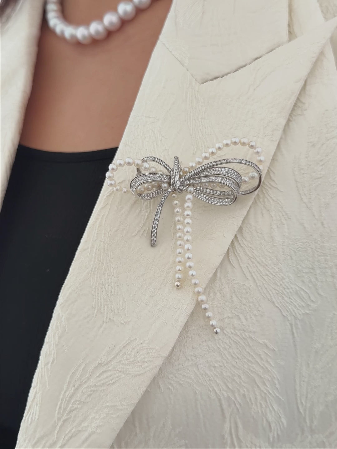 Pearl ribbon brooch styled for elegant evening and occasion wear.