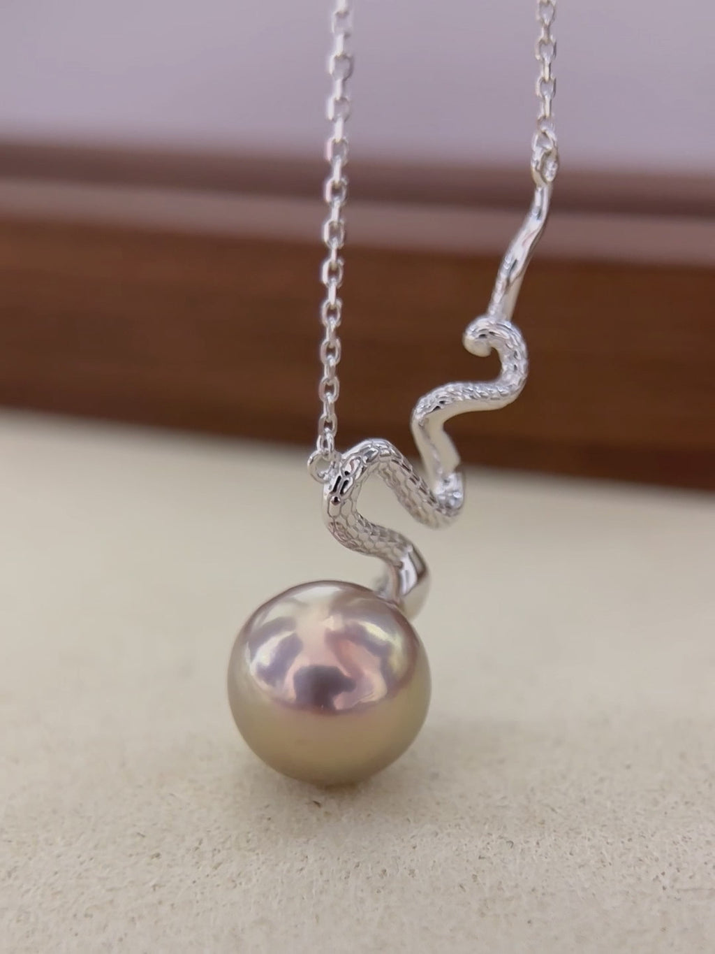 Iridescent freshwater pearl displaying brown, green and red colour shifts.