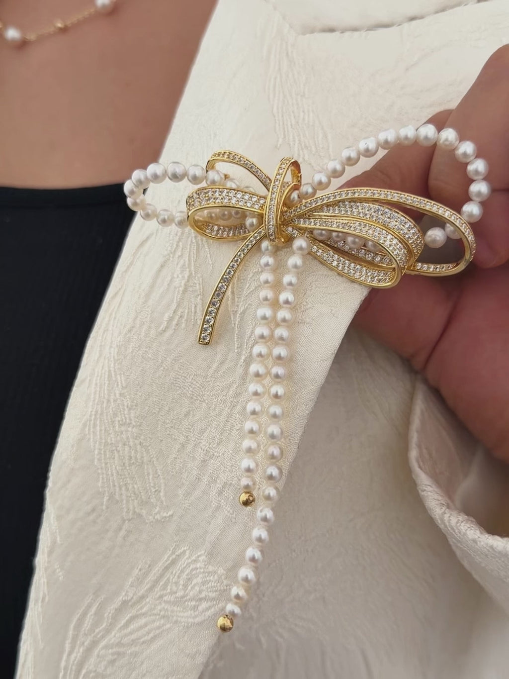 White freshwater pearl bow brooch worn as a statement blazer accessory.