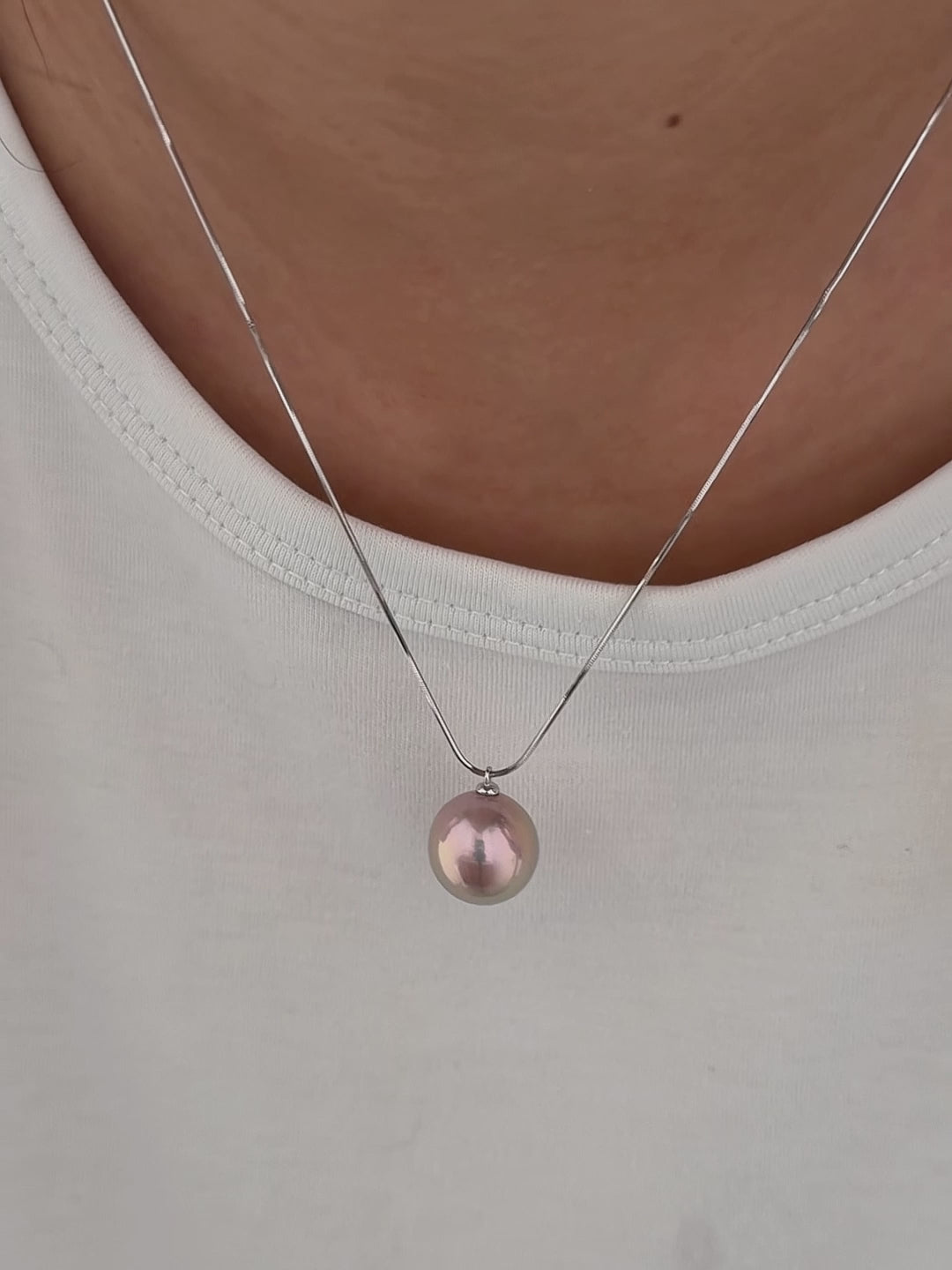 Model wearing a 14 mm metallic freshwater pearl pendant necklace.
Model wearing a red and green halo freshwater pearl pendant.
Model wearing a large iridescent freshwater pearl necklace with silver snake chain.