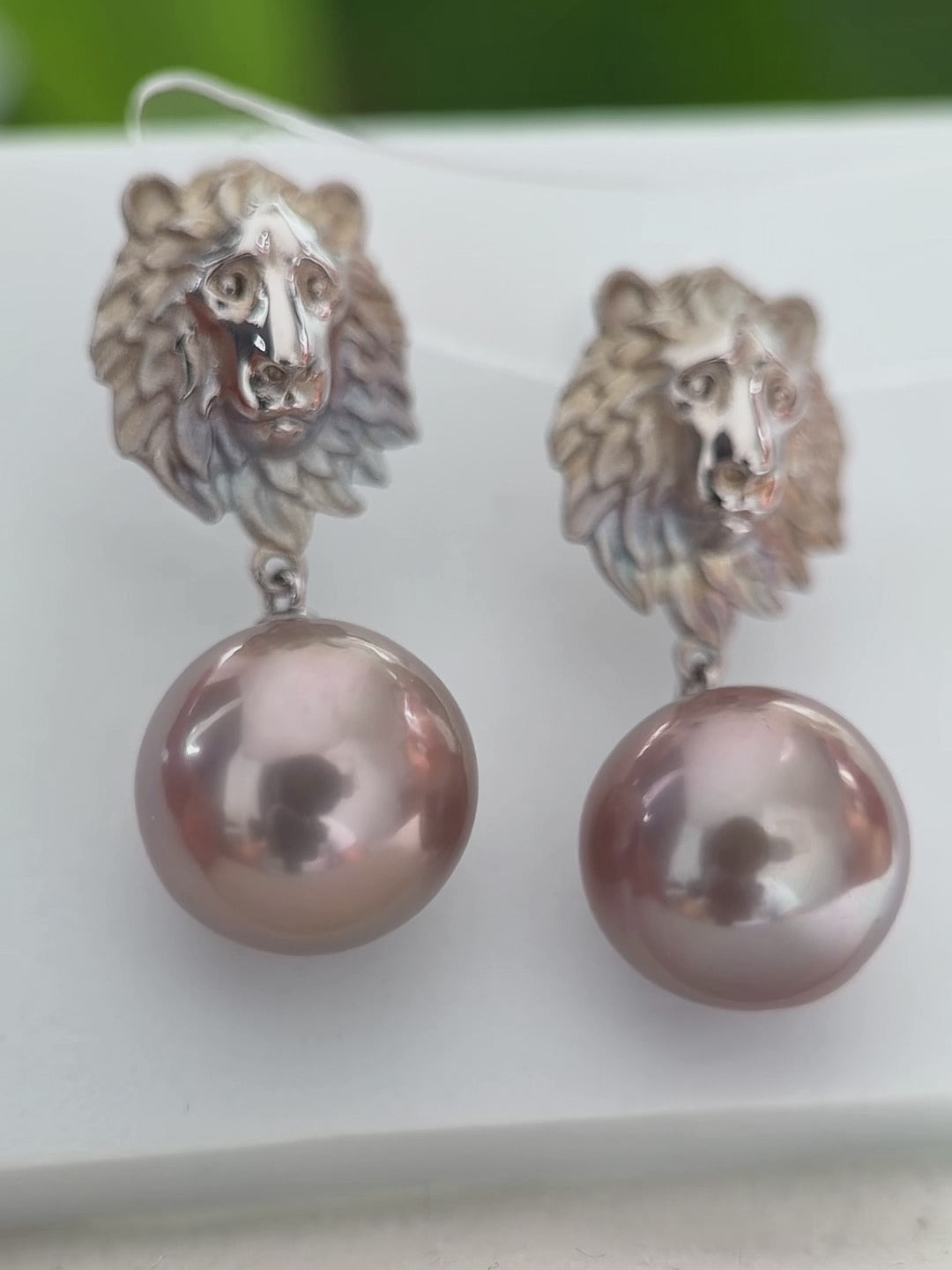 Large freshwater pearl earrings with a sculptural lion motif.