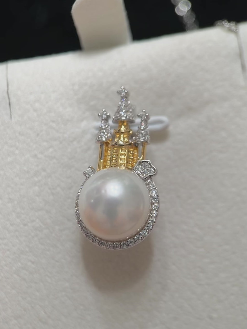 White pearl castle pendant photographed against a dark background.