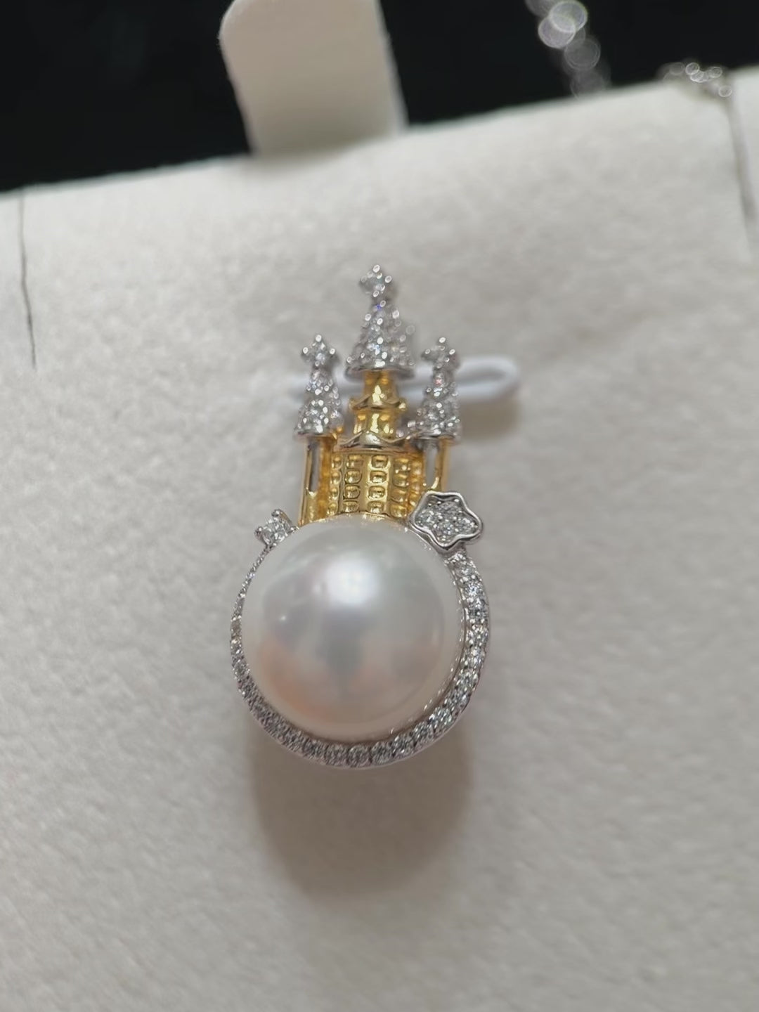 White pearl castle pendant photographed against a dark background.