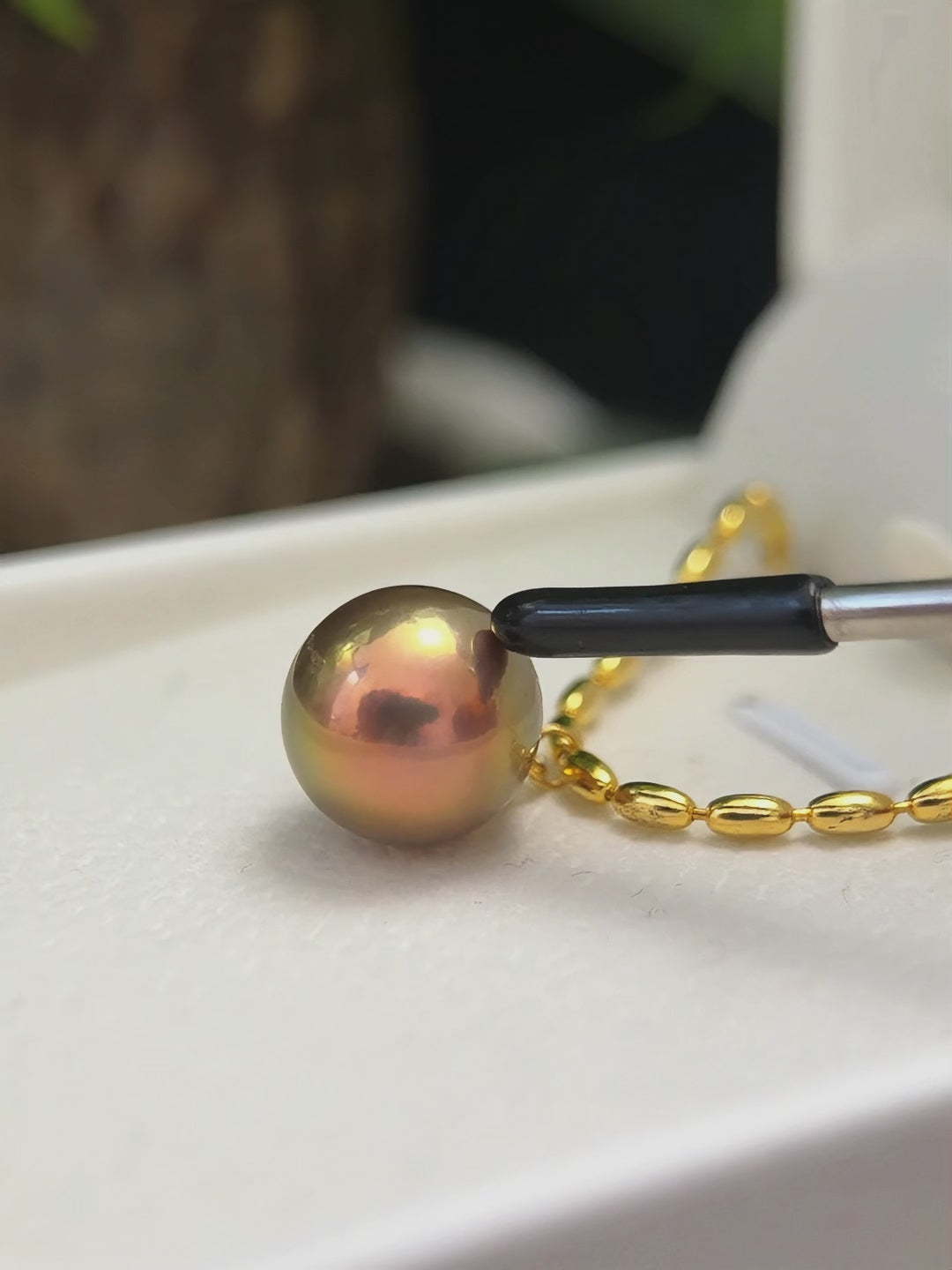 Close-up of a green pearl with soft purple iridescent halo.
Golden-green freshwater pearl necklace for special-occasion styling.
Large natural pearl necklace suspended from a sterling silver chain.